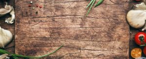 rustic cutting board surrounded by vegetables